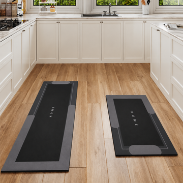 Black 2-piece kitchen mat set by Mattona: long runner and smaller HOME mat on a wooden kitchen floor